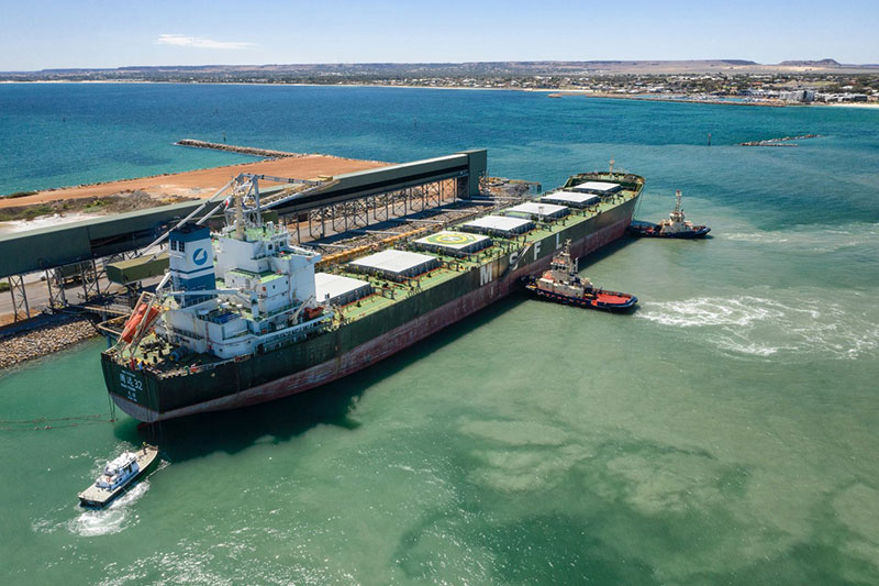 Large commercial ship being placed into position by 3 tug boats